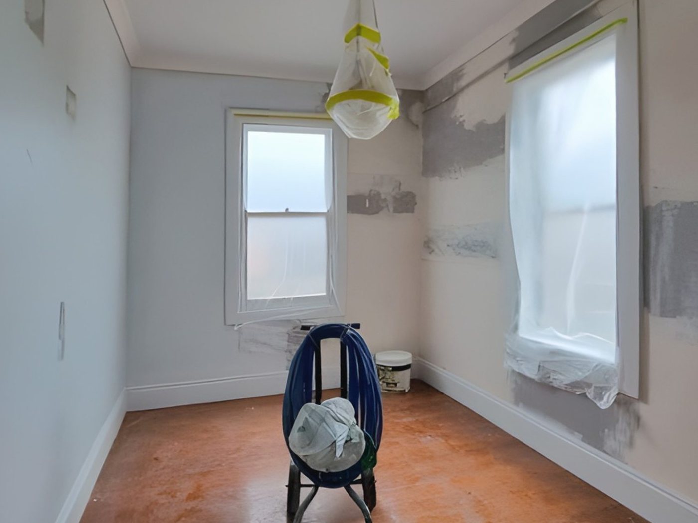 Before: Bedroom before painting, with patched walls and masked windows