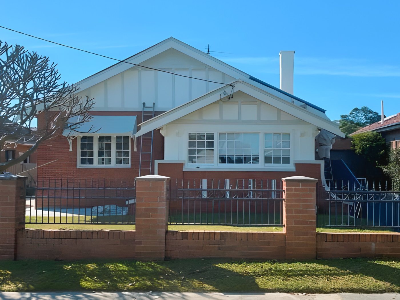 After: The same brick bungalow after its gables and trims were painted white