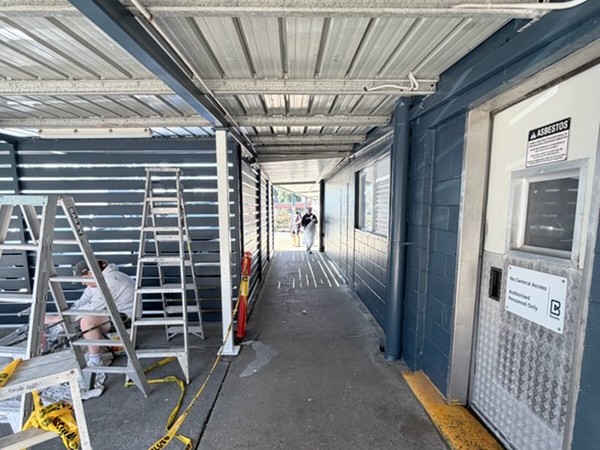 Before: Commercial walkway before painting, with ladders and the area taped off