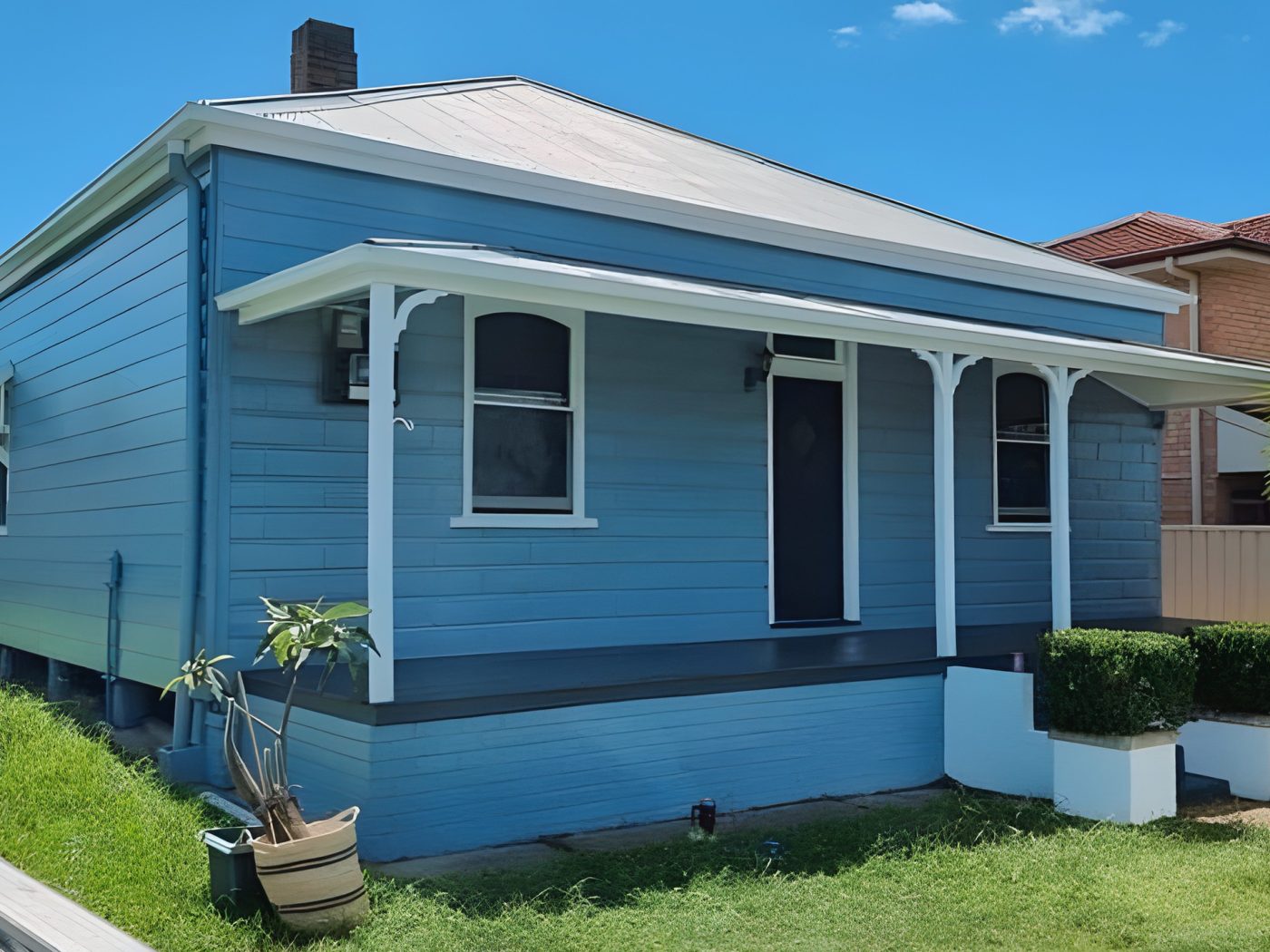 After: The same weatherboard cottage after its exterior repaint in blue with white trims