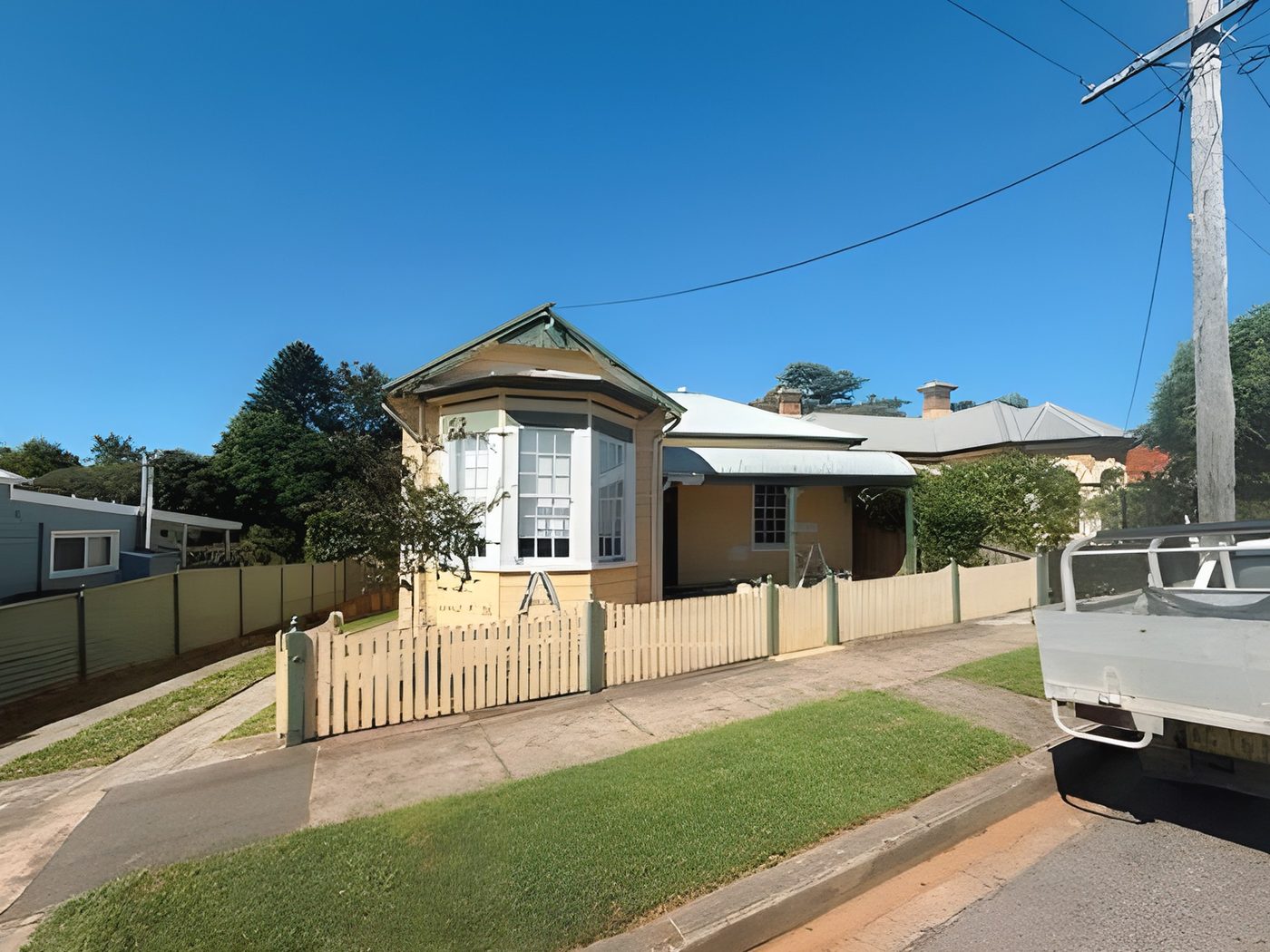 Before: Federation cottage before painting, in cream with a timber picket fence