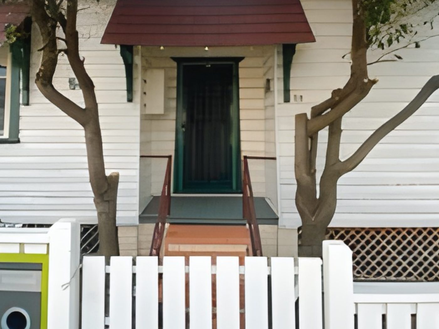 Before: Weatherboard cottage entry before painting, with red awnings and green trims