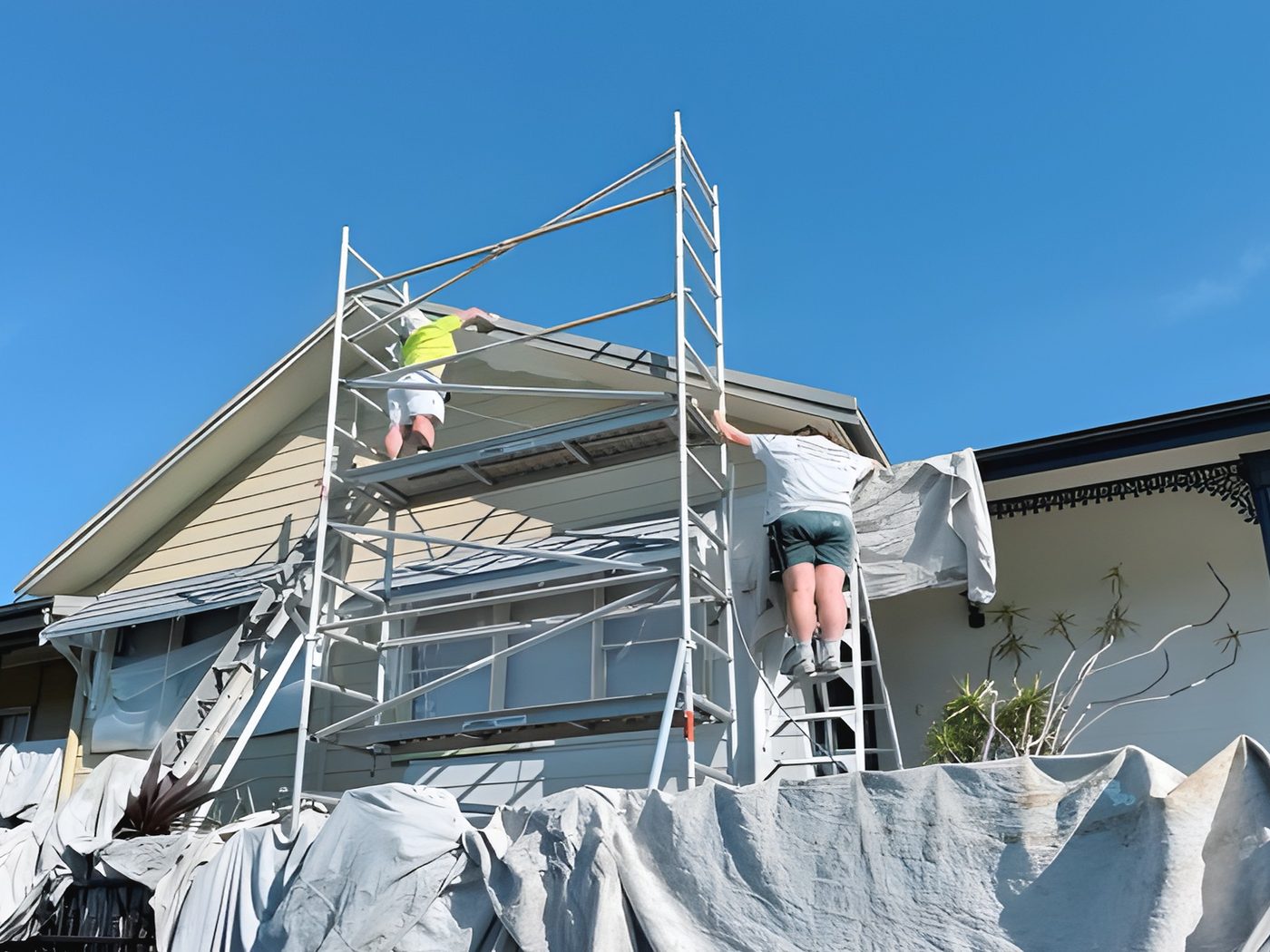 Before: Two storey weatherboard home during painting, with scaffolding and drop sheets