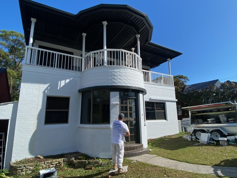 After: The same two storey brick home after its exterior was painted white