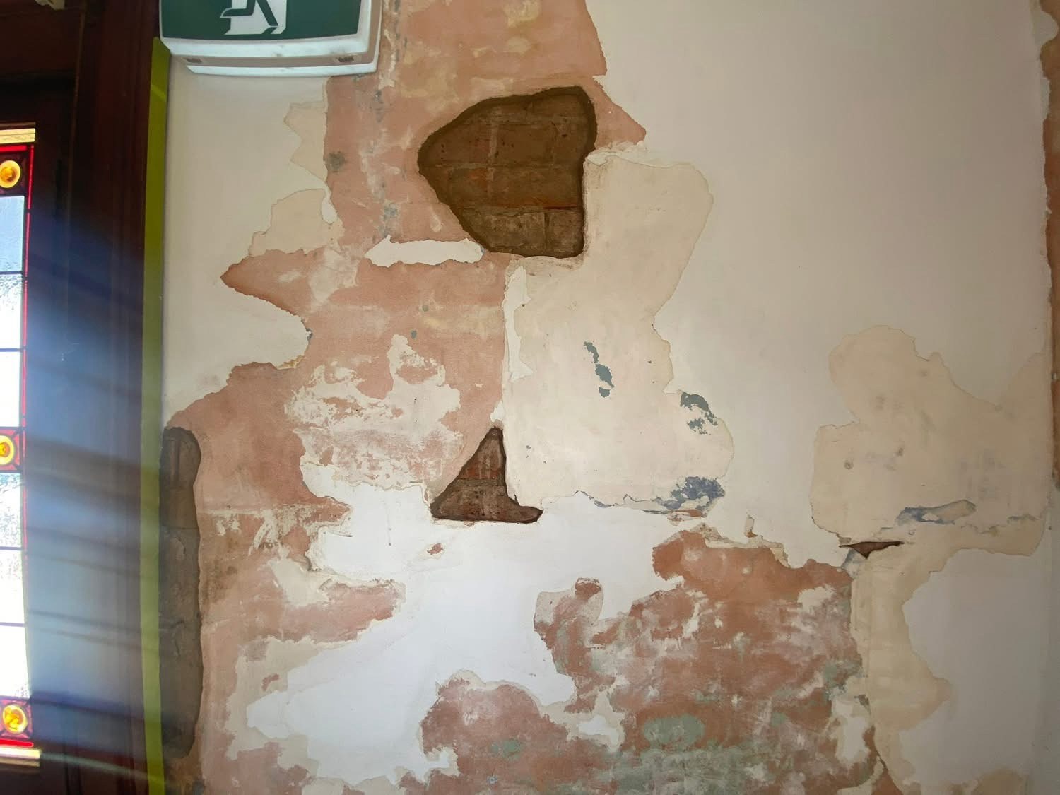 Before: Heritage wall before rectification, with rising damp, crumbling plaster and exposed brick