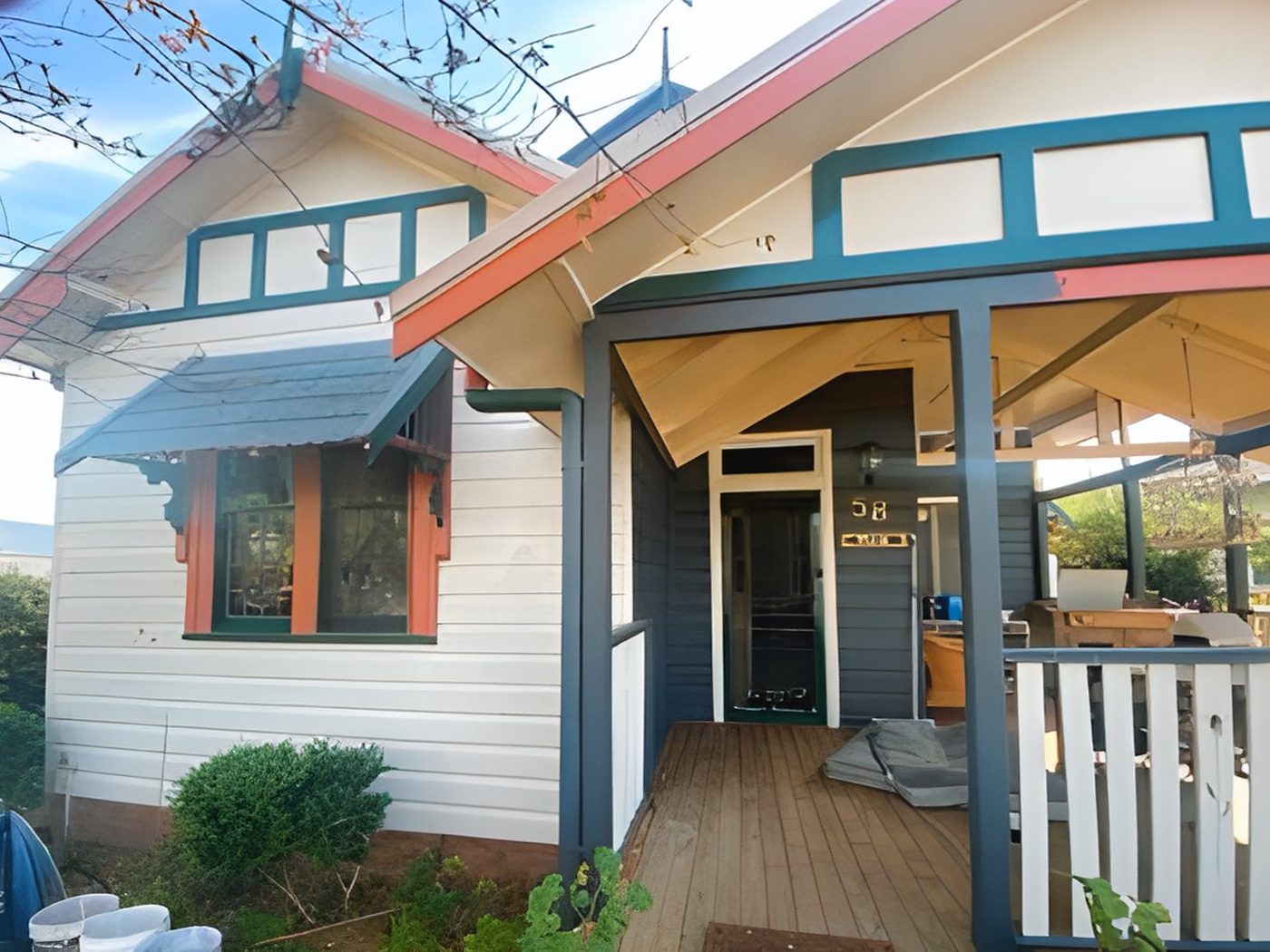 Before: Weatherboard cottage before restoration, with faded orange and green trims