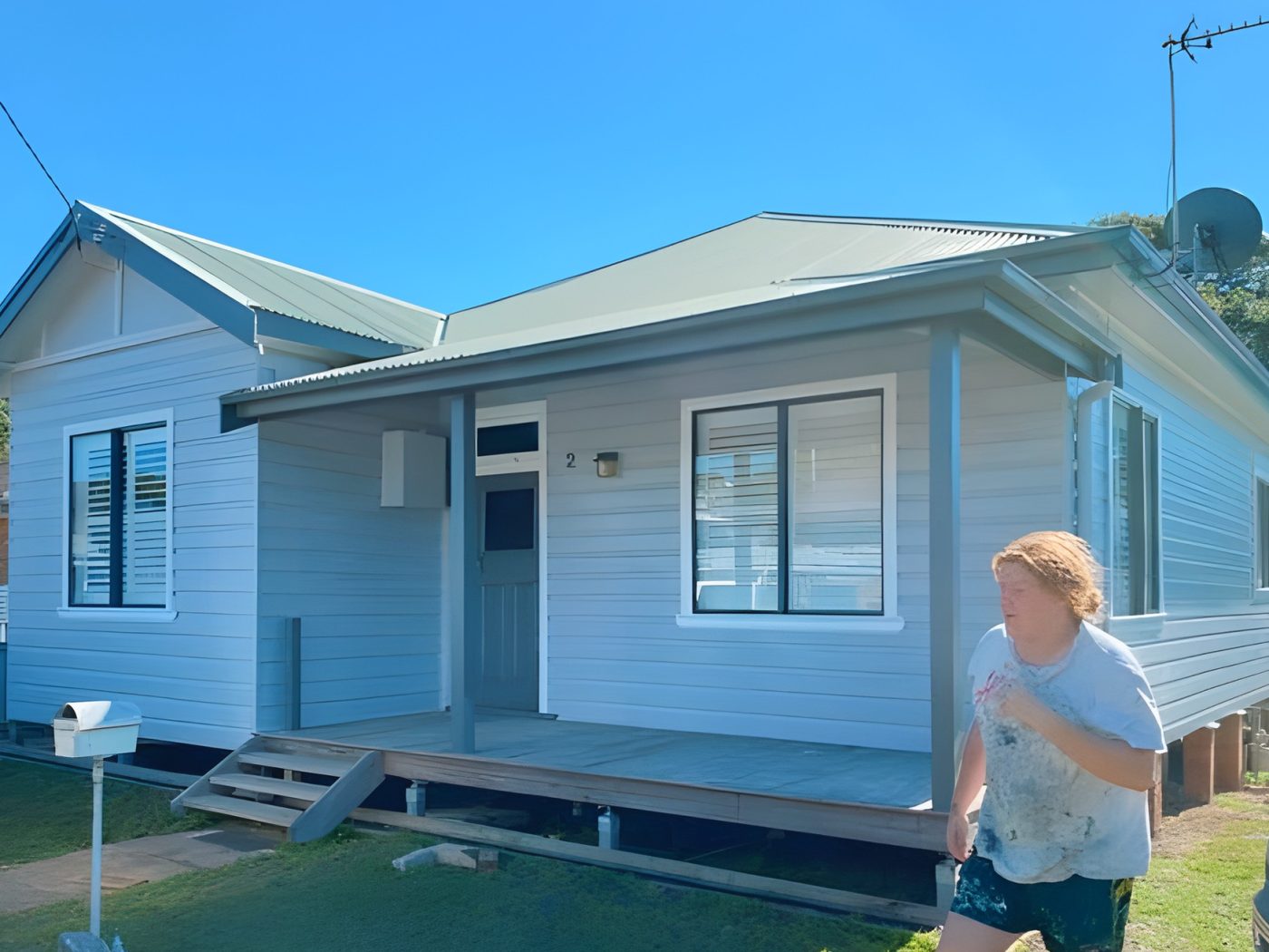After: The same weatherboard home after its exterior repaint in pale blue-grey