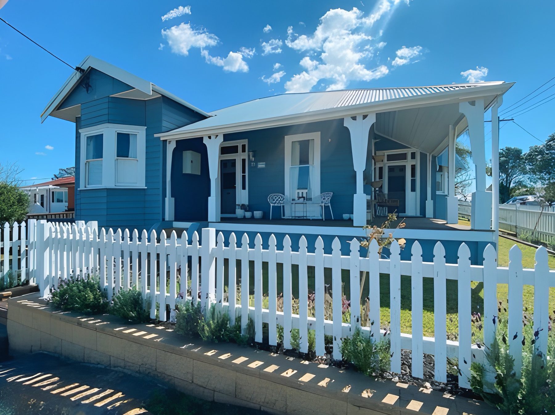 Blue weatherboard heritage home with white trims and picket fence, freshly painted by Newcastle painters
